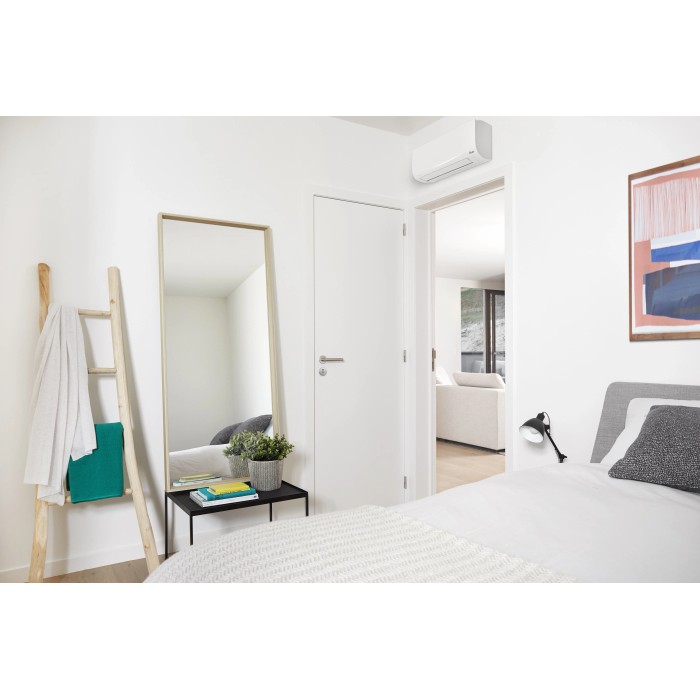 Condizionatore t.b.t. in camera da letto moderna con specchio e scala.