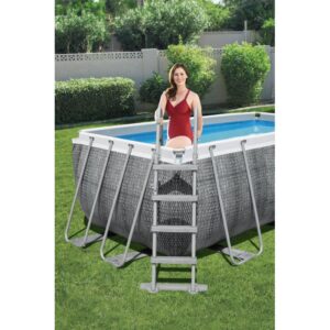 Piscina fuori terra rettangolare con scaletta e donna in costume rosso in giardino.