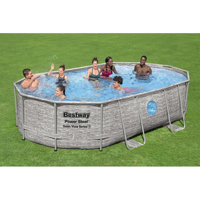 Piscina ovale con struttura in acciaio e motivo pietra, piena di persone in giardino.