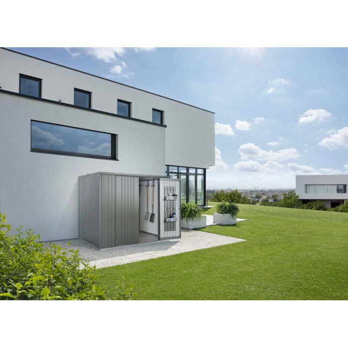 Armadio da esterno Biohort Large, grigio quarzo metallizzato, con porta aperta e attrezzi da giardino davanti a una casa moderna.