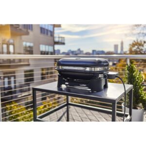 Barbecue elettrico t.b.t. nero compatto su un tavolo da esterno.