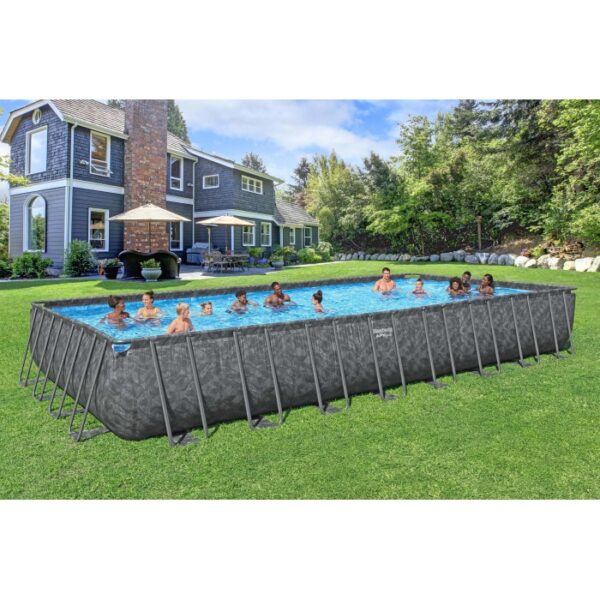 Piscina fuori terra rettangolare con rivestimento grigio e persone che nuotano in giardino.