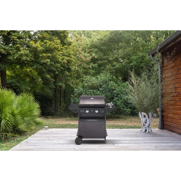 Barbecue a gas nero t.b.t. con ripiani laterali su un patio in legno in giardino.
