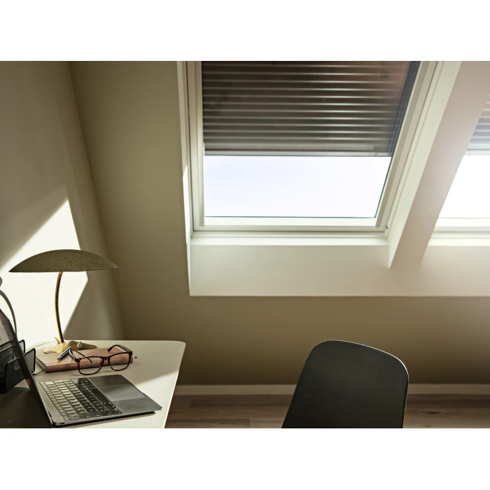 Tapparella solare Velux SSL CK02, grigio scuro, parzialmente aperta su una finestra per tetti in mansarda.