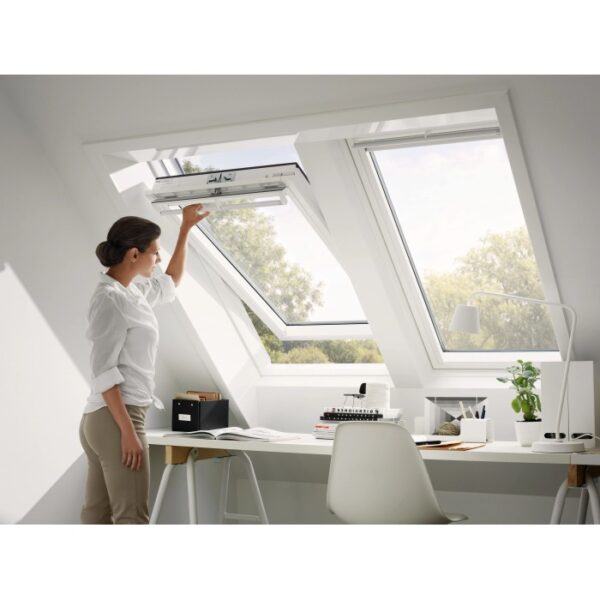Donna apre finestra a bilico Velux in plastica, 66x140 cm, in mansarda.