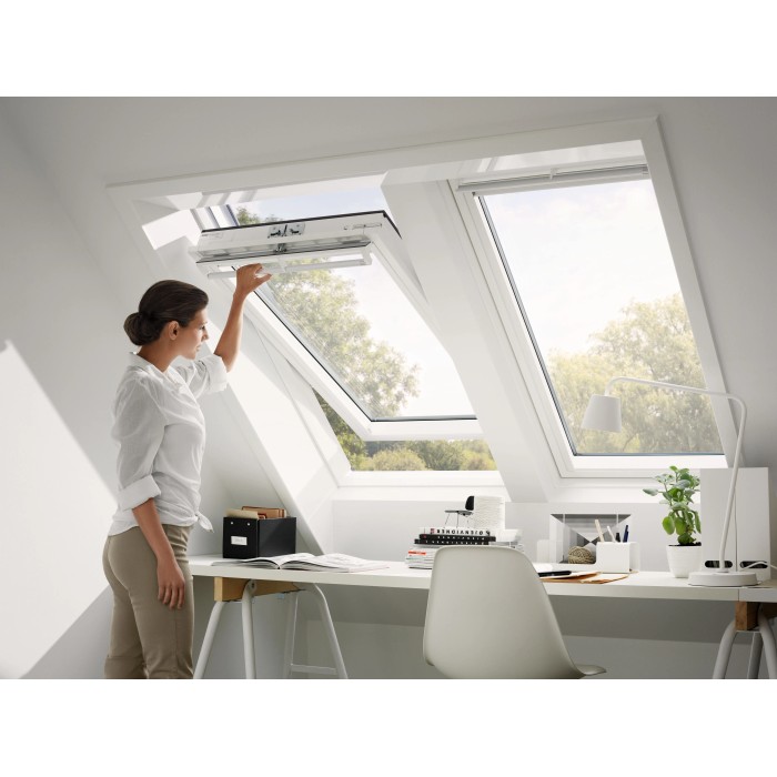 Donna apre finestra a bilico Velux in plastica, 66x140 cm, in mansarda.