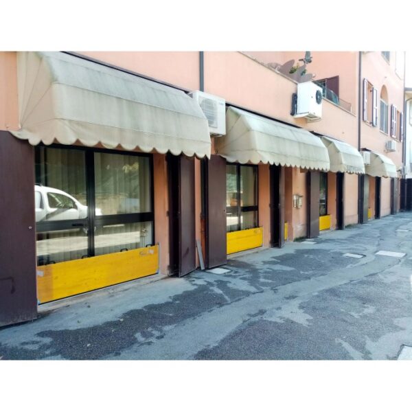 Facciata di edificio con tende da sole e barriere di protezione dalle inondazioni.