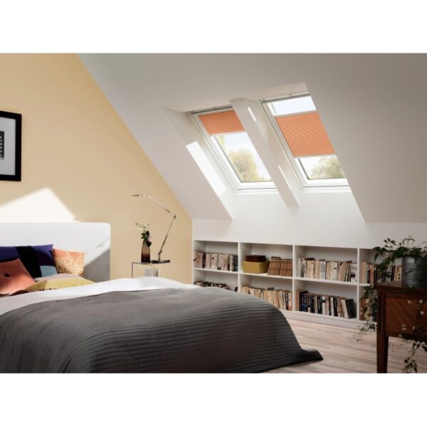 Camera da letto luminosa con due finestre per tetti Velux GGL MK06 2070 bianche con tende arancioni.