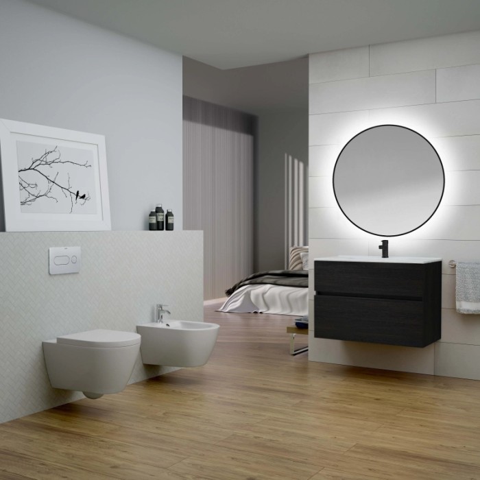 Bagno con specchio rotondo a LED e mobile lavabo scuro.
