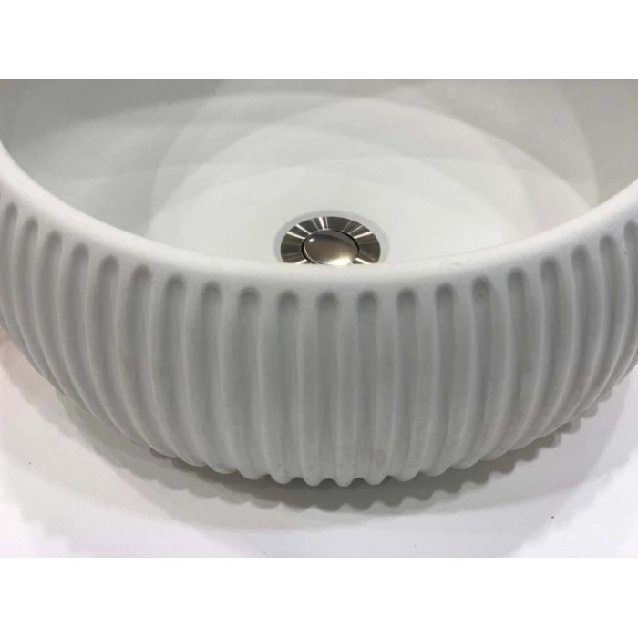 Lavabo d'appoggio t.b.t. bianco con superficie a coste e scarico color argento.