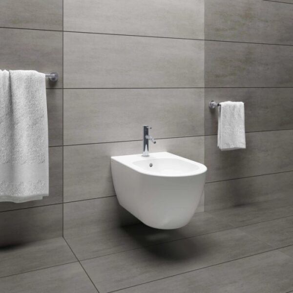 Bidet moderno sospeso in bianco con rubinetto su parete grigia.