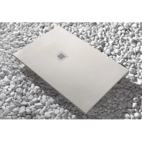 Piatto doccia t.b.t. beige con scarico quadrato su ciottoli bianchi.