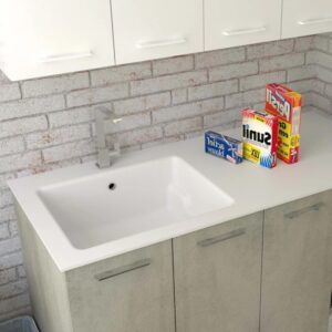 Mobile lavabo con lavabo bianco e rubinetto davanti a una parete di mattoni.
